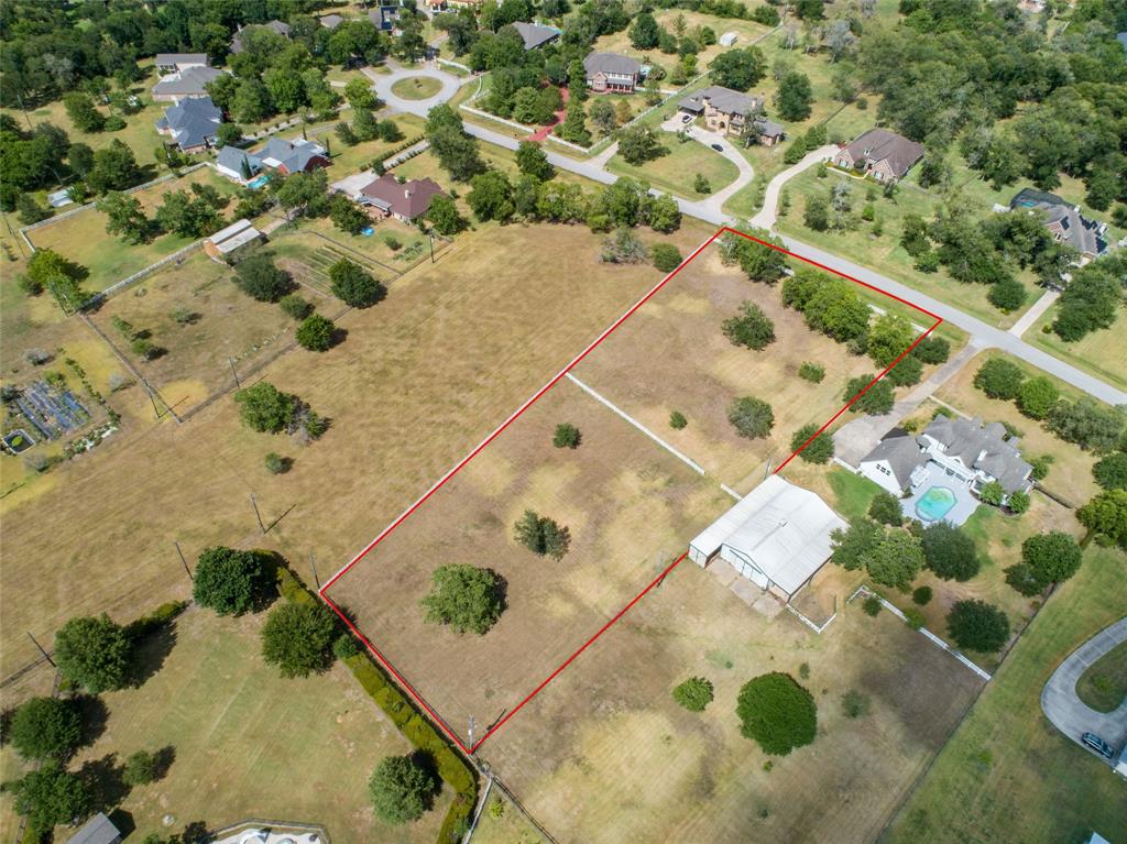 An aerial view showcasing the expansive 2-acre lot at 7318 Rolling Meadow Drive, Richmond, TX. This property offers the perfect blend of country living with city convenience, surrounded by beautiful homes in a tranquil neighborhood. The clear boundaries highlight the spacious area available for building your dream home, with plenty of room for gardens, recreational spaces, or even a pool.