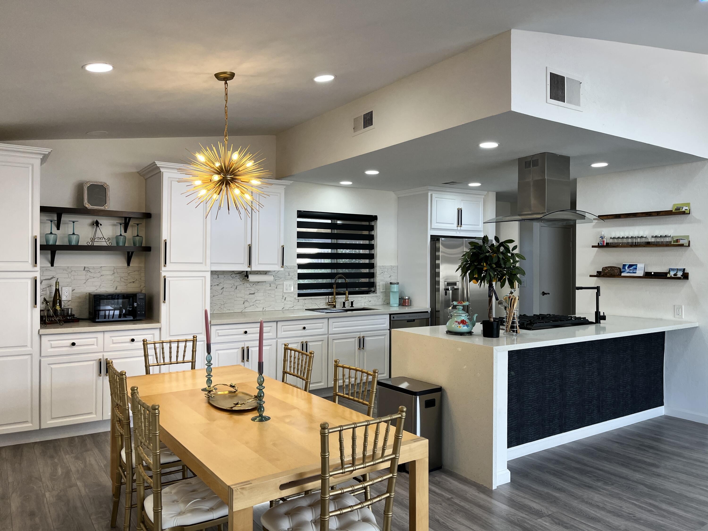 a kitchen with stainless steel appliances kitchen island granite countertop a table chairs and a refrigerator