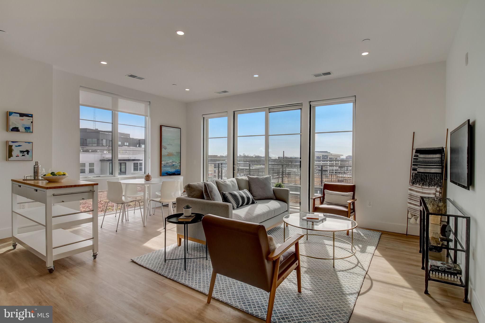 a living room with furniture a flat screen tv and a floor to ceiling window