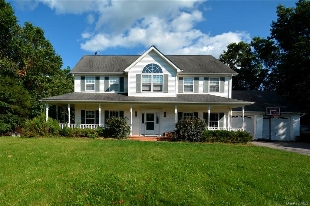 View of front of home with a porch, a garage, and a front lawn