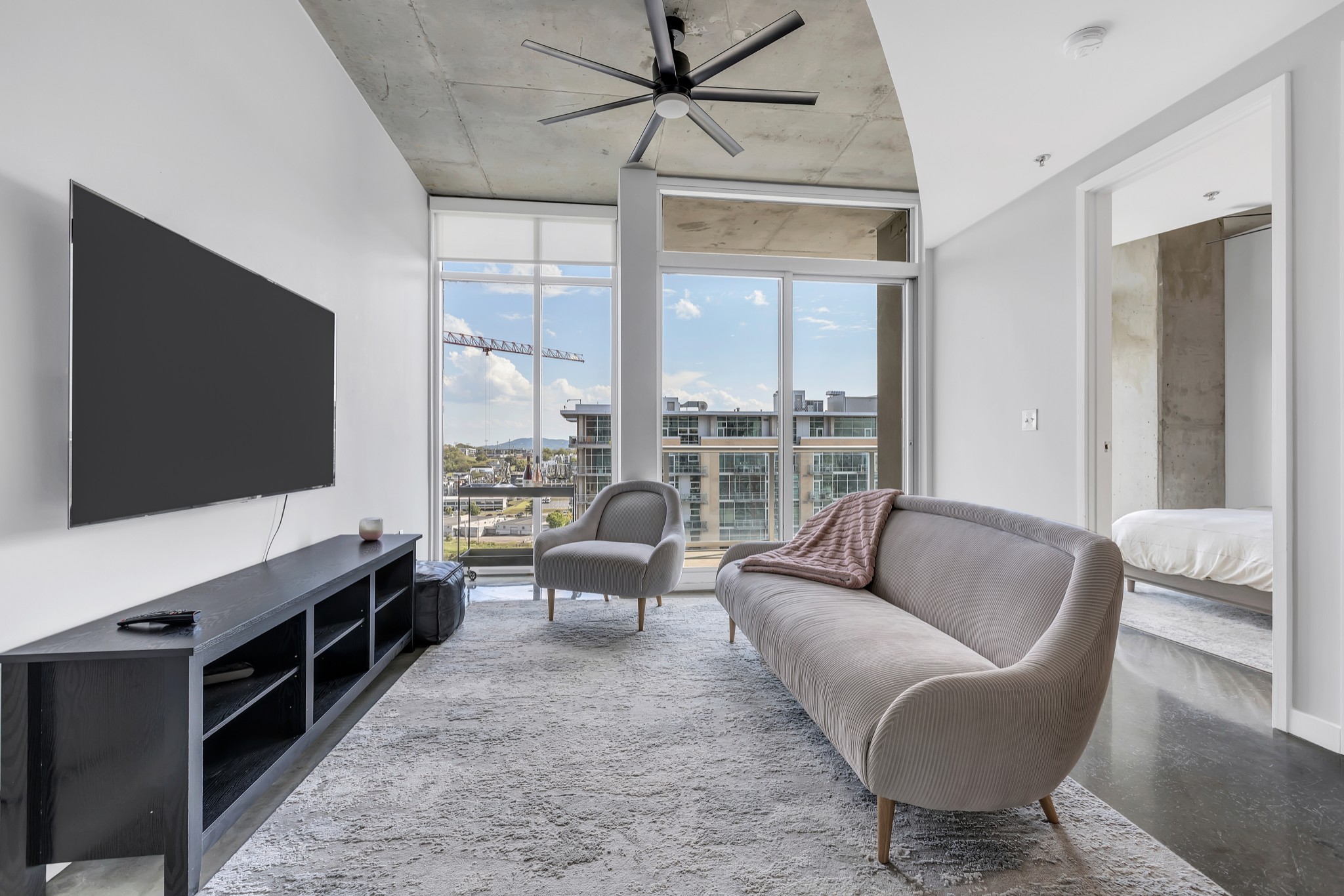 a living room with furniture a flat screen tv and a floor to ceiling window