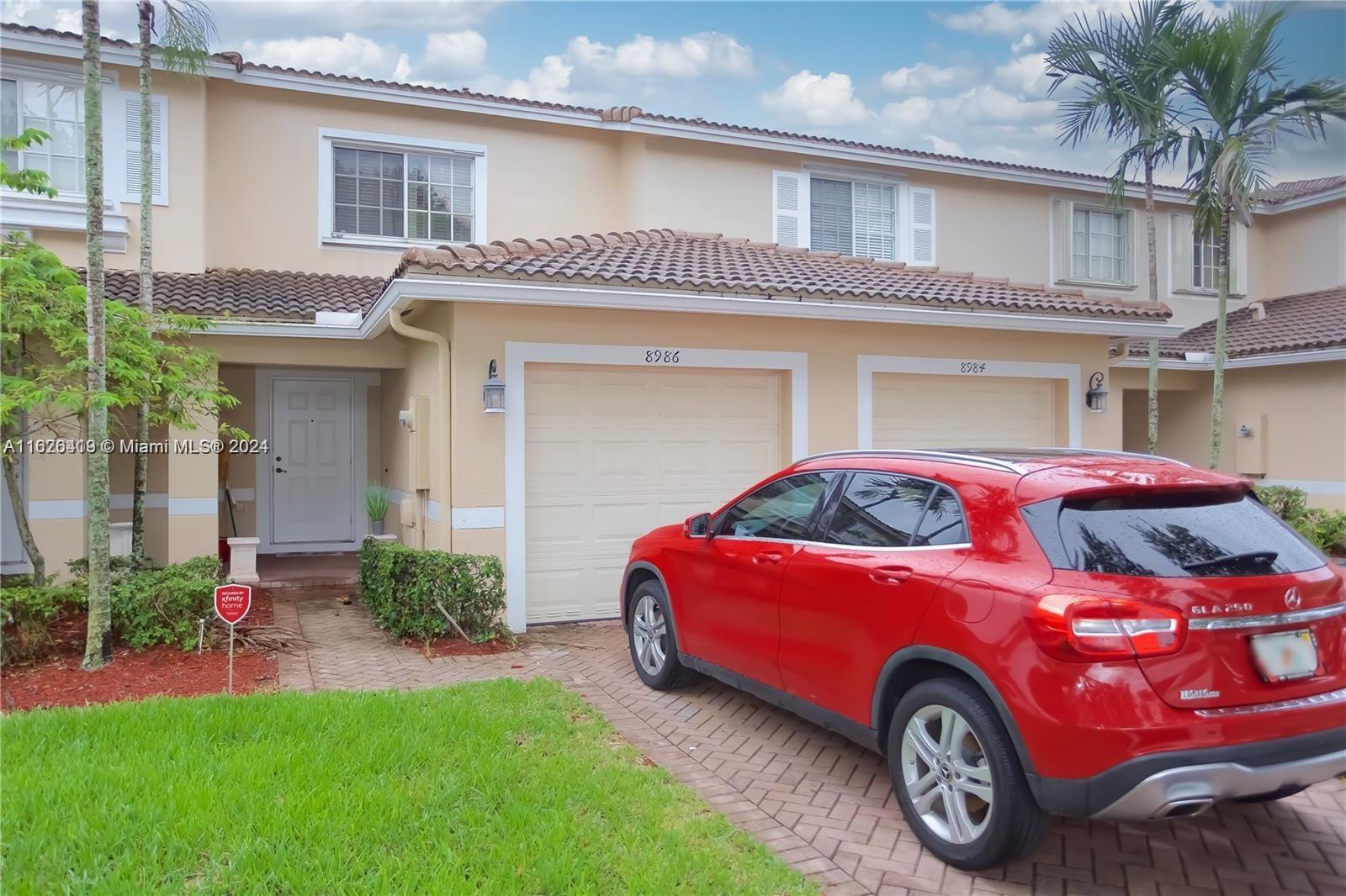 a front view of a house with a garden and parking