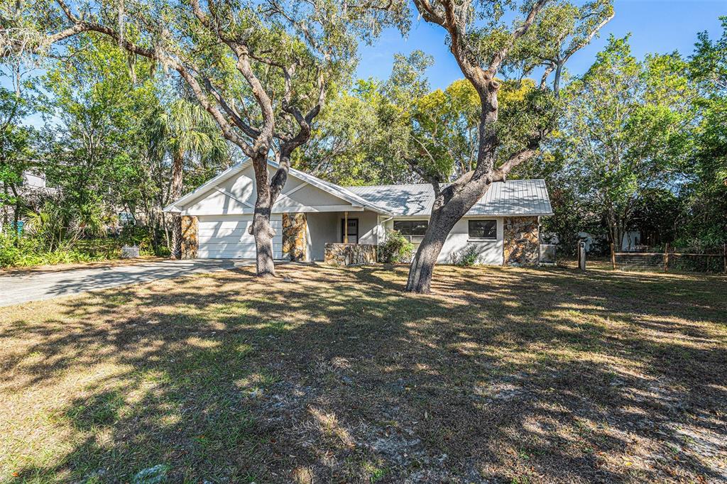 a front view of a house with a yard and large trees