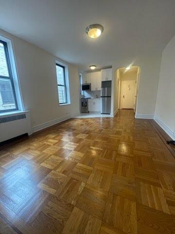 a view of empty room with wooden floor and fan