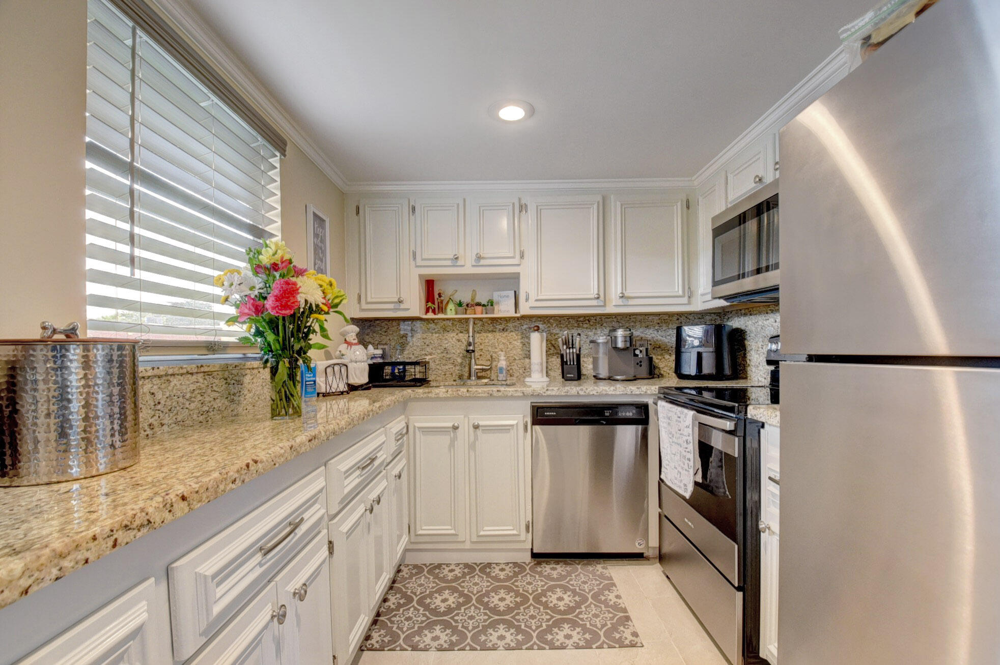 a kitchen with kitchen island granite countertop a sink stainless steel appliances counter space and cabinets