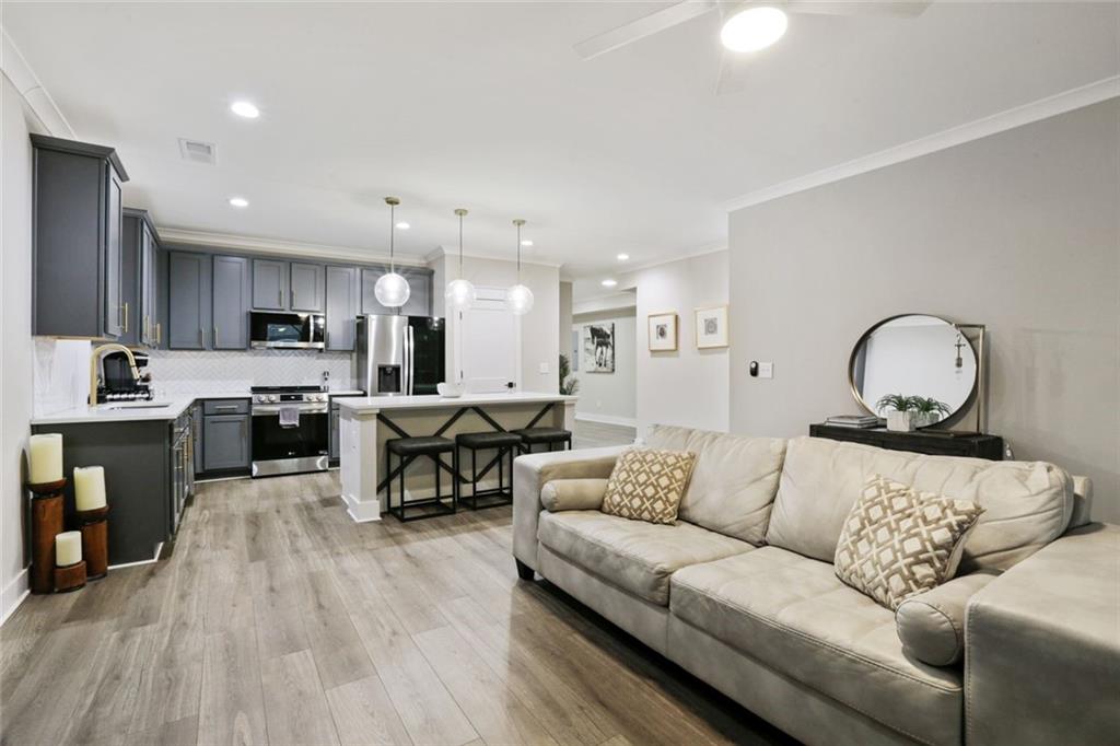 a living room with furniture kitchen view and a wooden floor