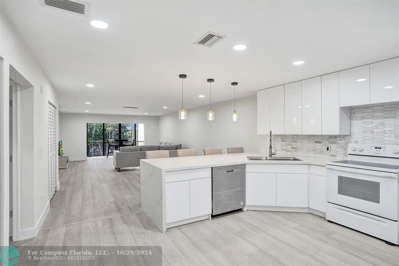 a large white kitchen with a sink and cabinets