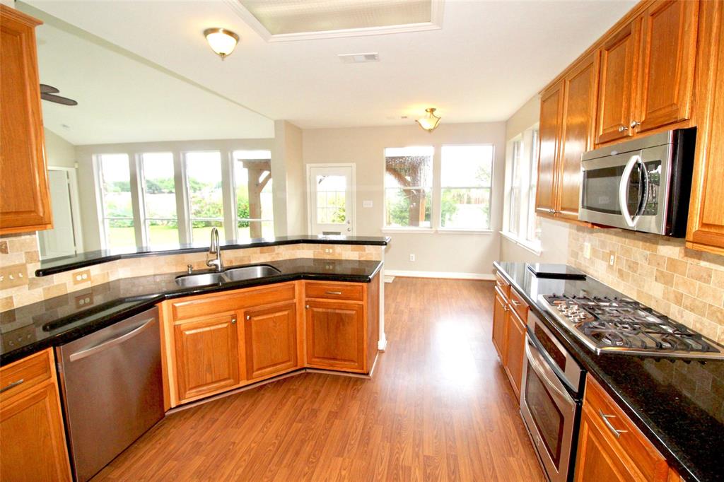 View of the open concept kitchen which looks out to the den and features laminate flooring, granite countertops and stainless steel appliances. The refrigerator in conveniently included in the lease.