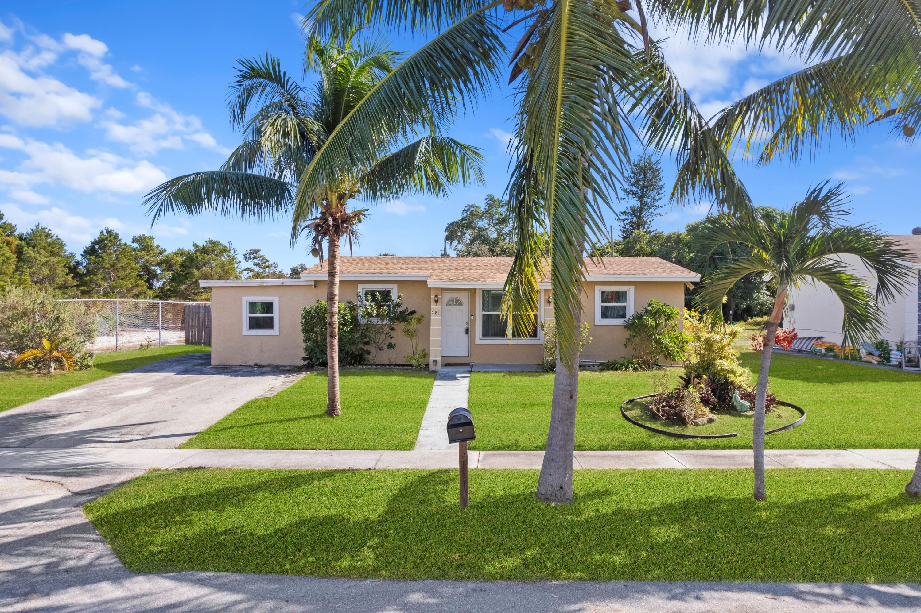 a view of a house with a yard and palm trees