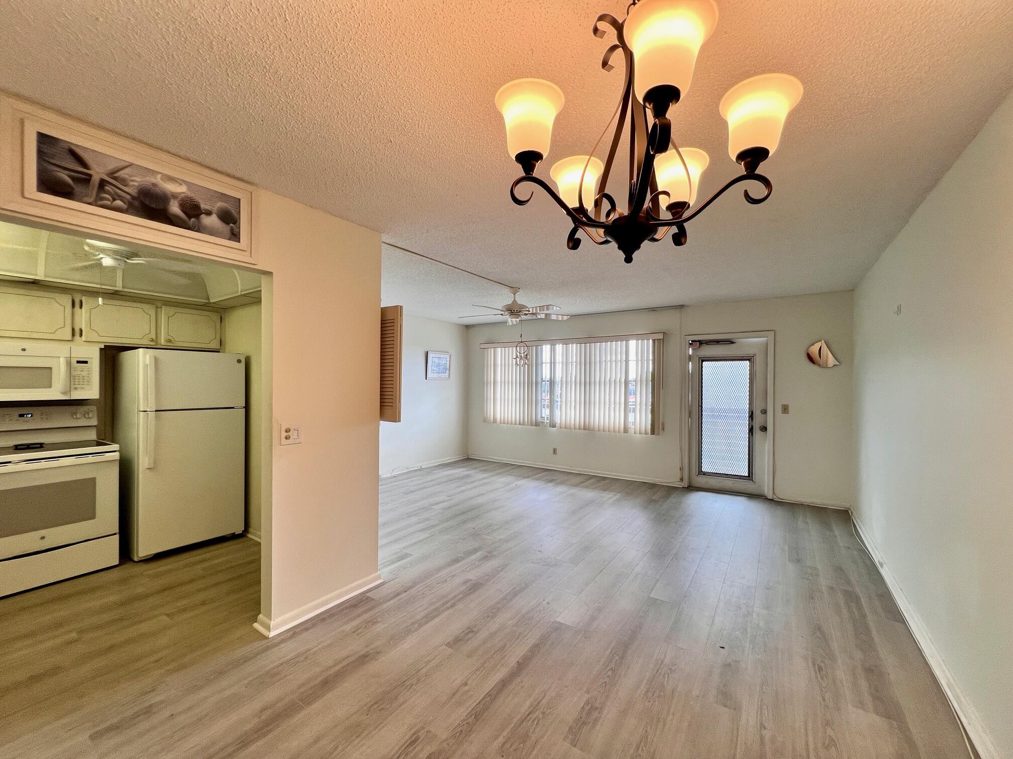 a view of a room with wooden floor ceiling fan and window