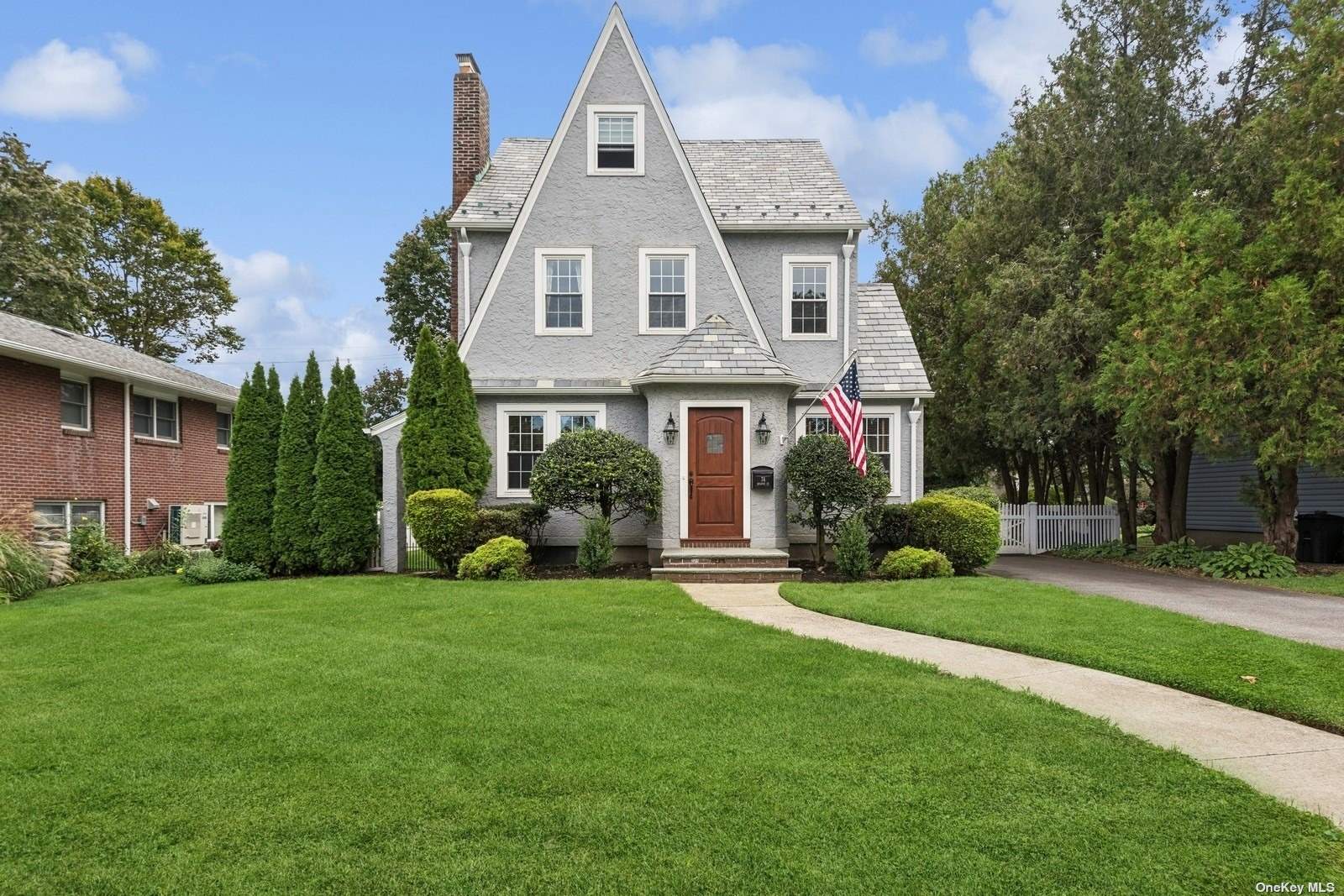 a front view of a house with a garden and trees