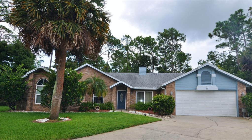 front view of house with a yard and palm trees