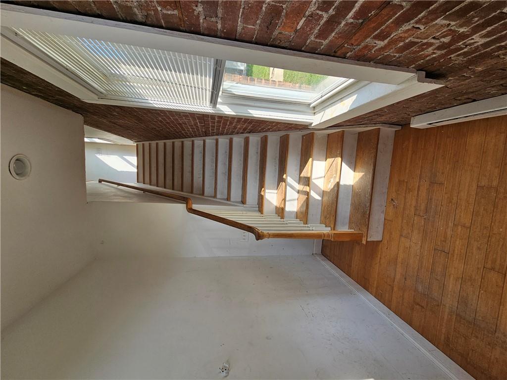 Stairway with a baseboard heating unit, brick wall, and hardwood / wood-style floors