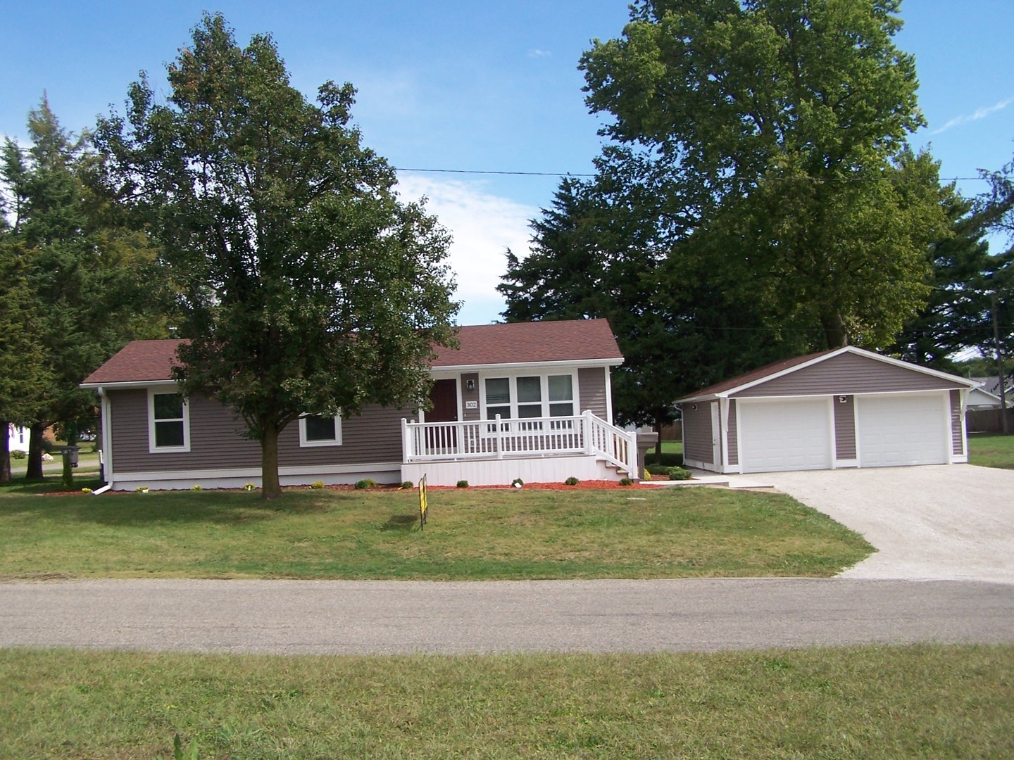 a front view of a house with a garden and trees