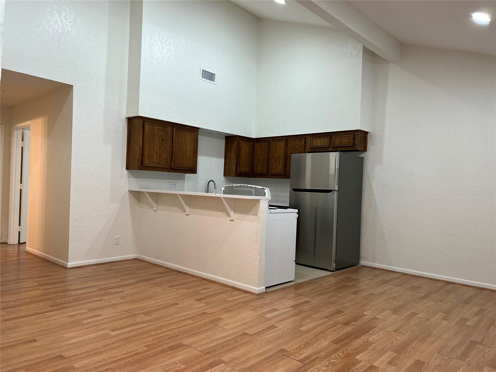 a view of kitchen with stainless steel appliances wooden floor and chair