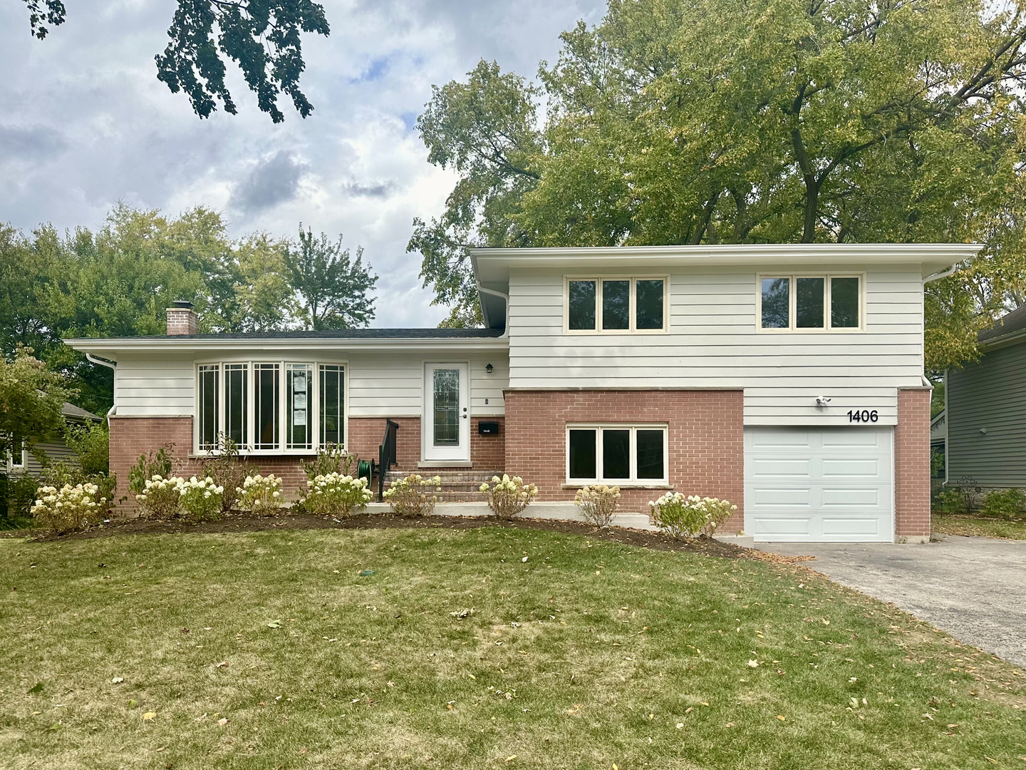 a front view of house with yard and trees in the background