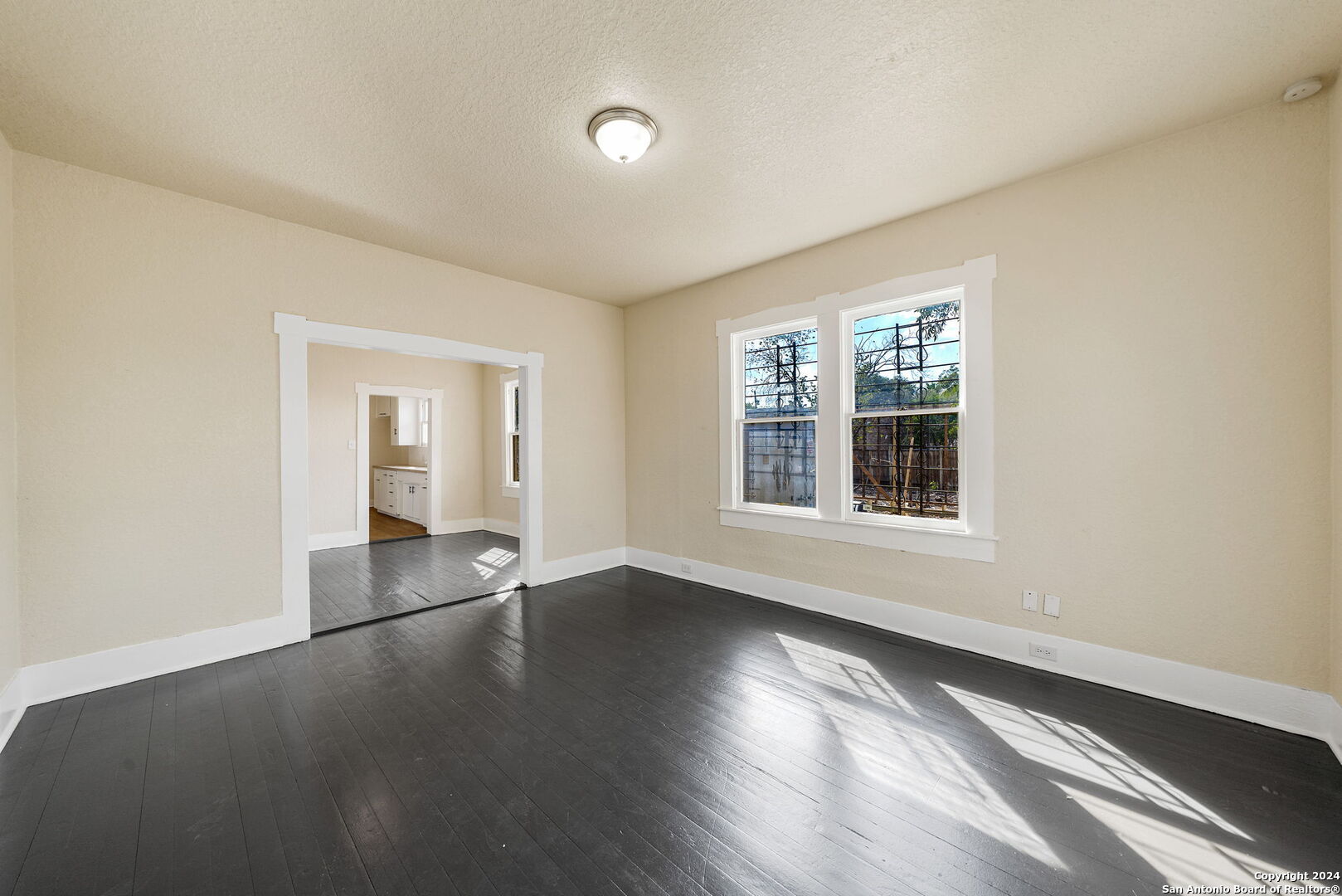 an empty room with wooden floor and windows