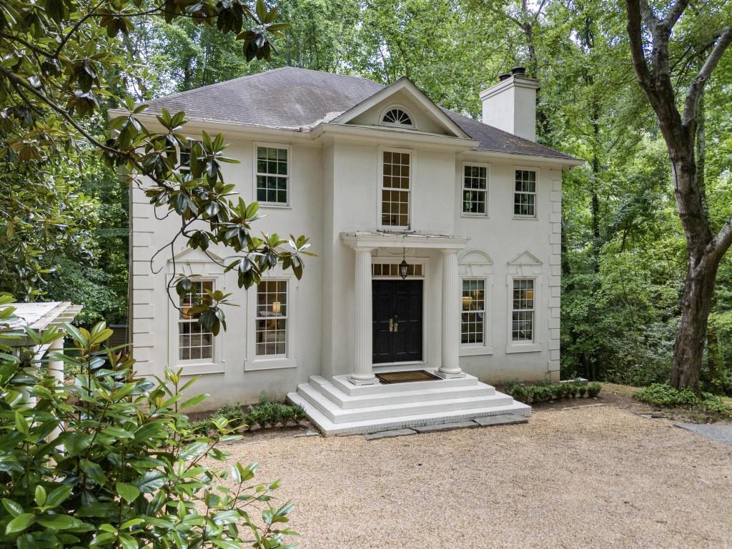 a front view of a house with a garden and trees