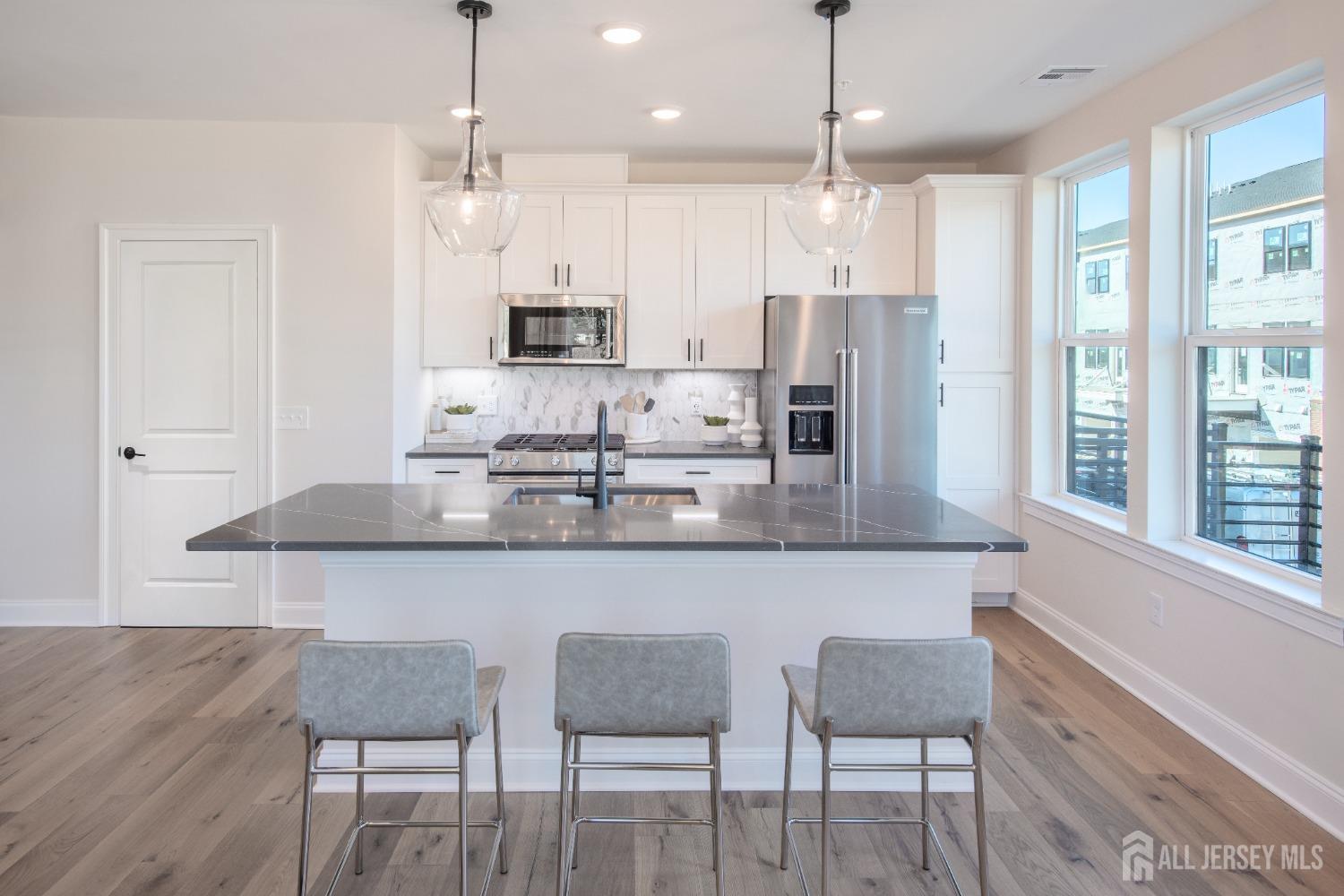 a kitchen with kitchen island granite countertop a dining table chairs and white cabinets