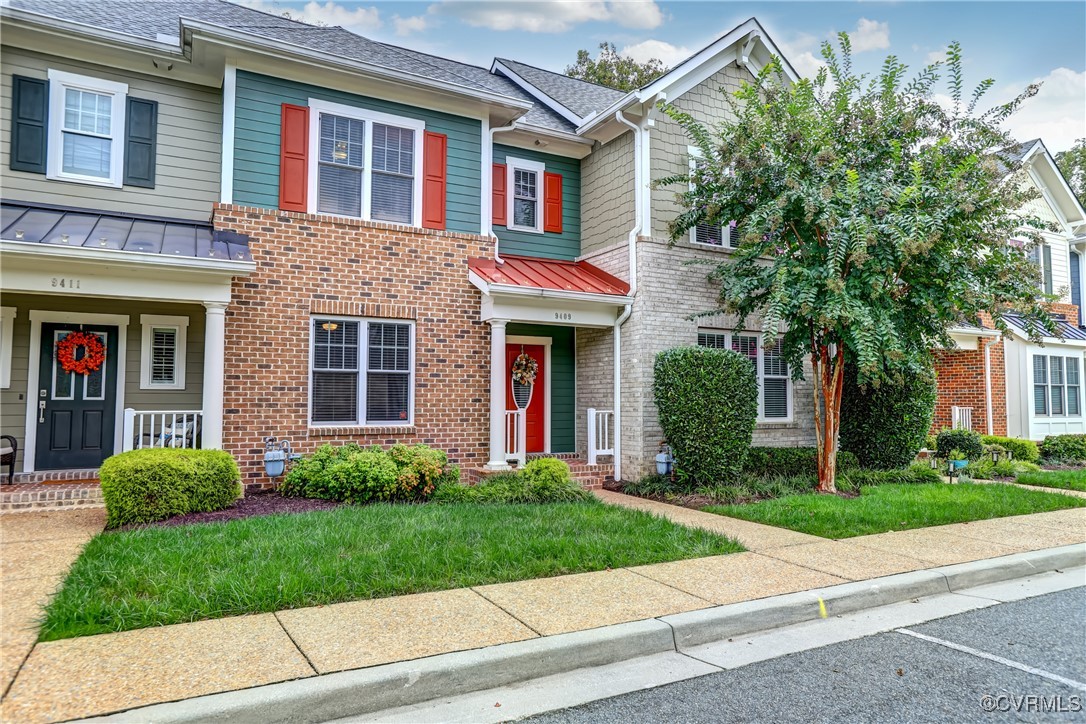 a view of a brick house with a yard plants next to a road