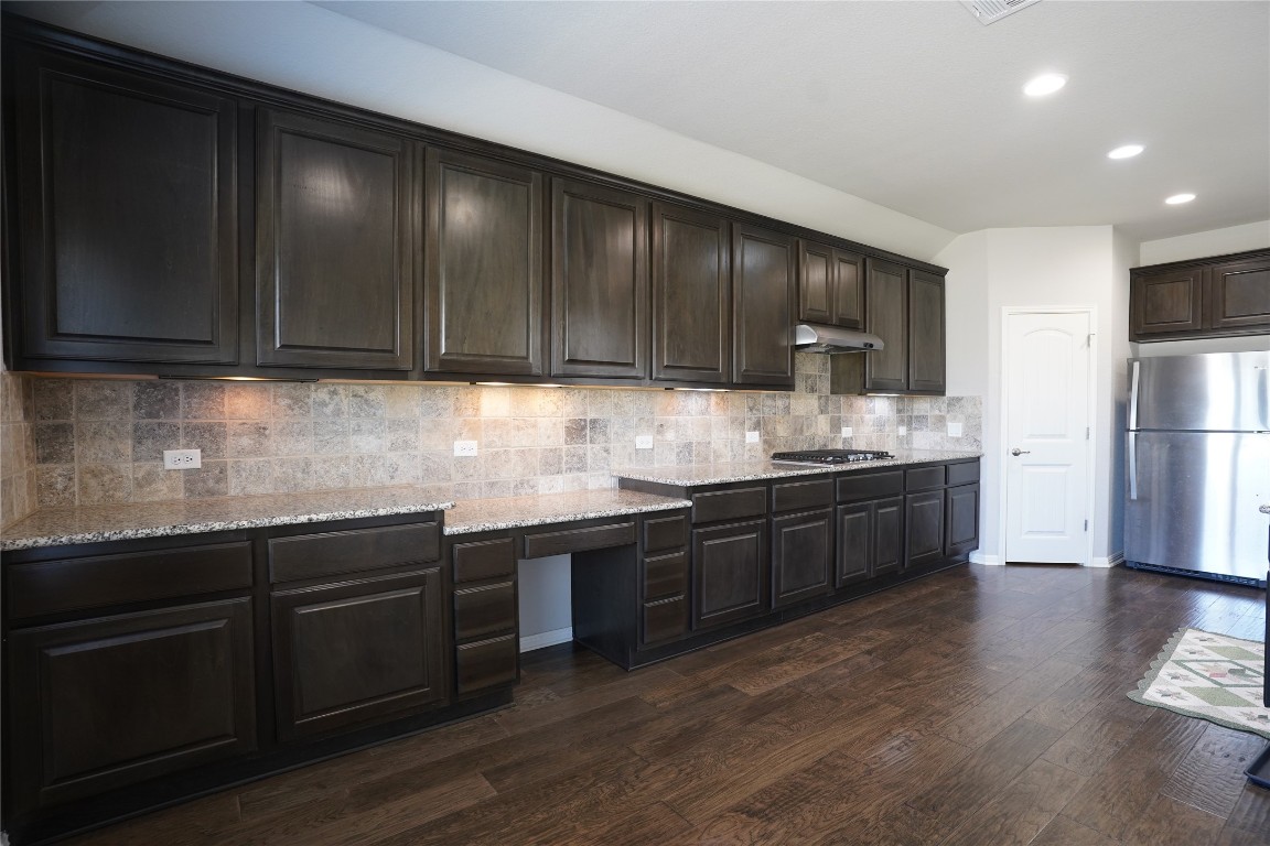 a kitchen with granite countertop wooden cabinets a sink and stainless steel appliances