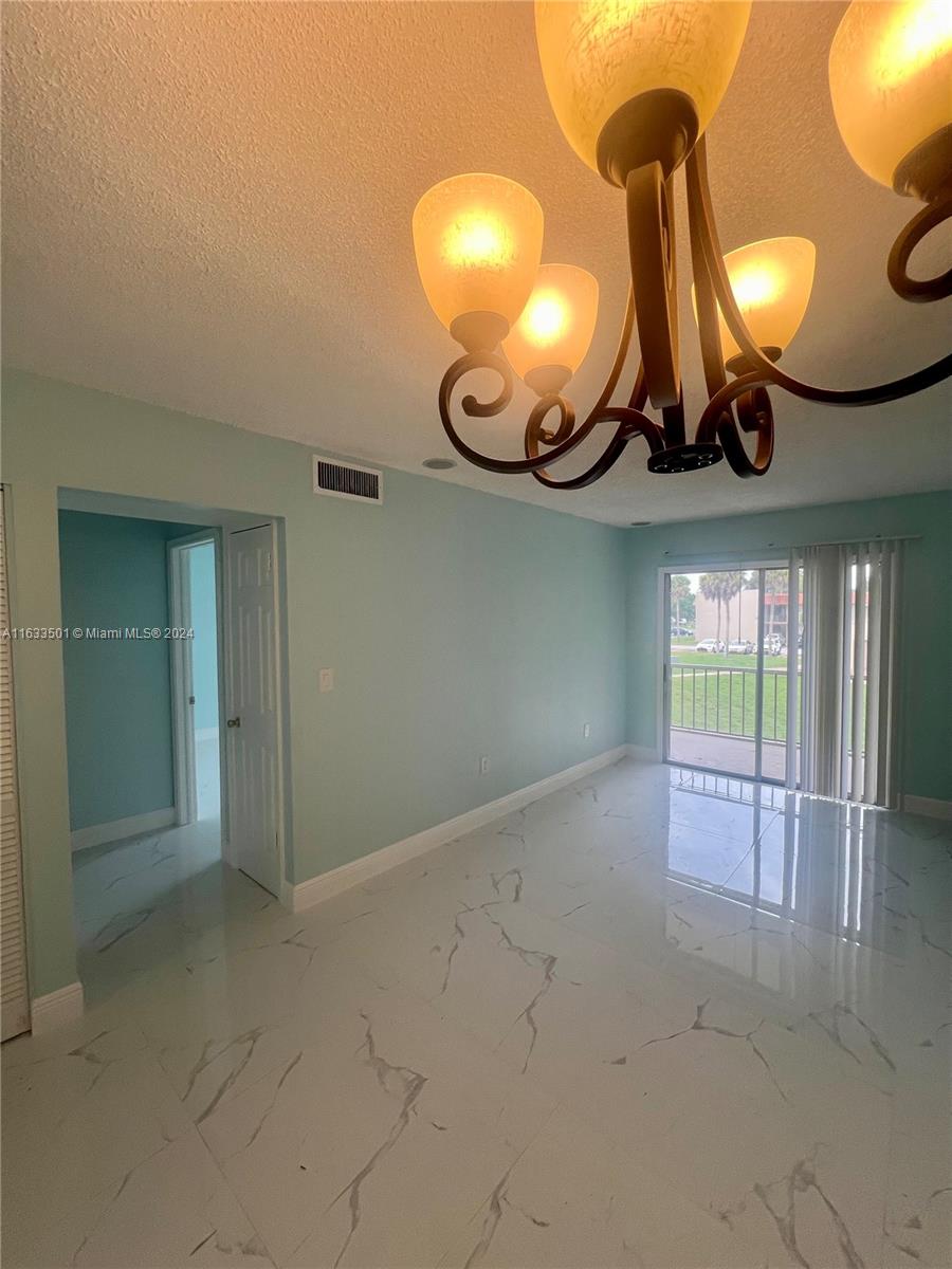 an empty room with a large window and chandelier