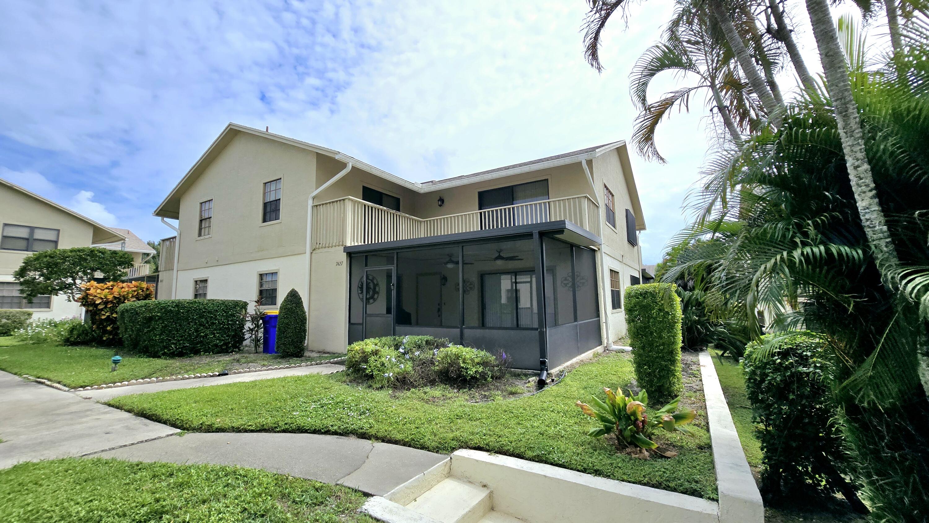 a front view of a house with a yard and potted plants