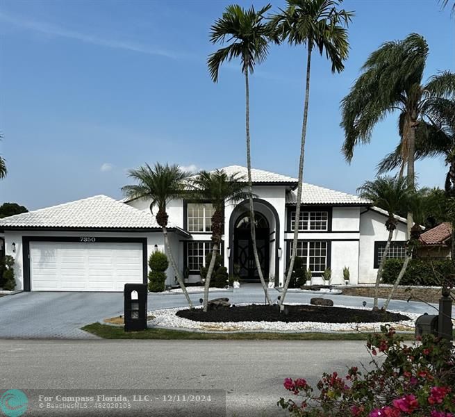 a front view of a house with garage and plants