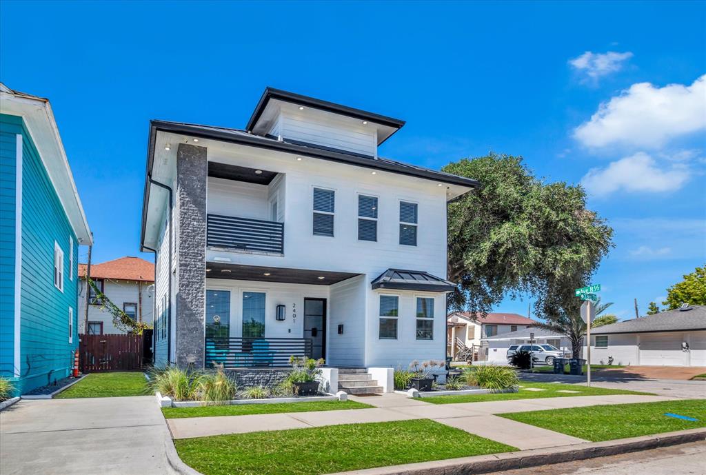 Modern two-story home with a white exterior, contrasting dark trim, and a stone accent column.