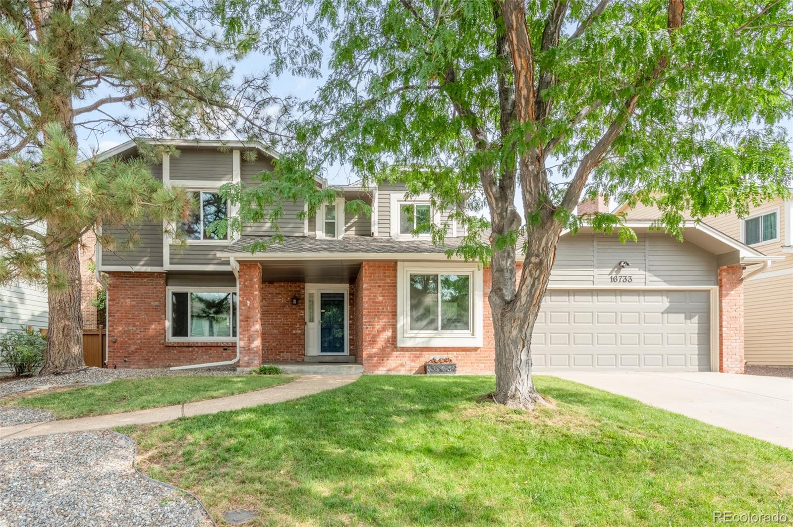 front view of a house with a yard and an trees