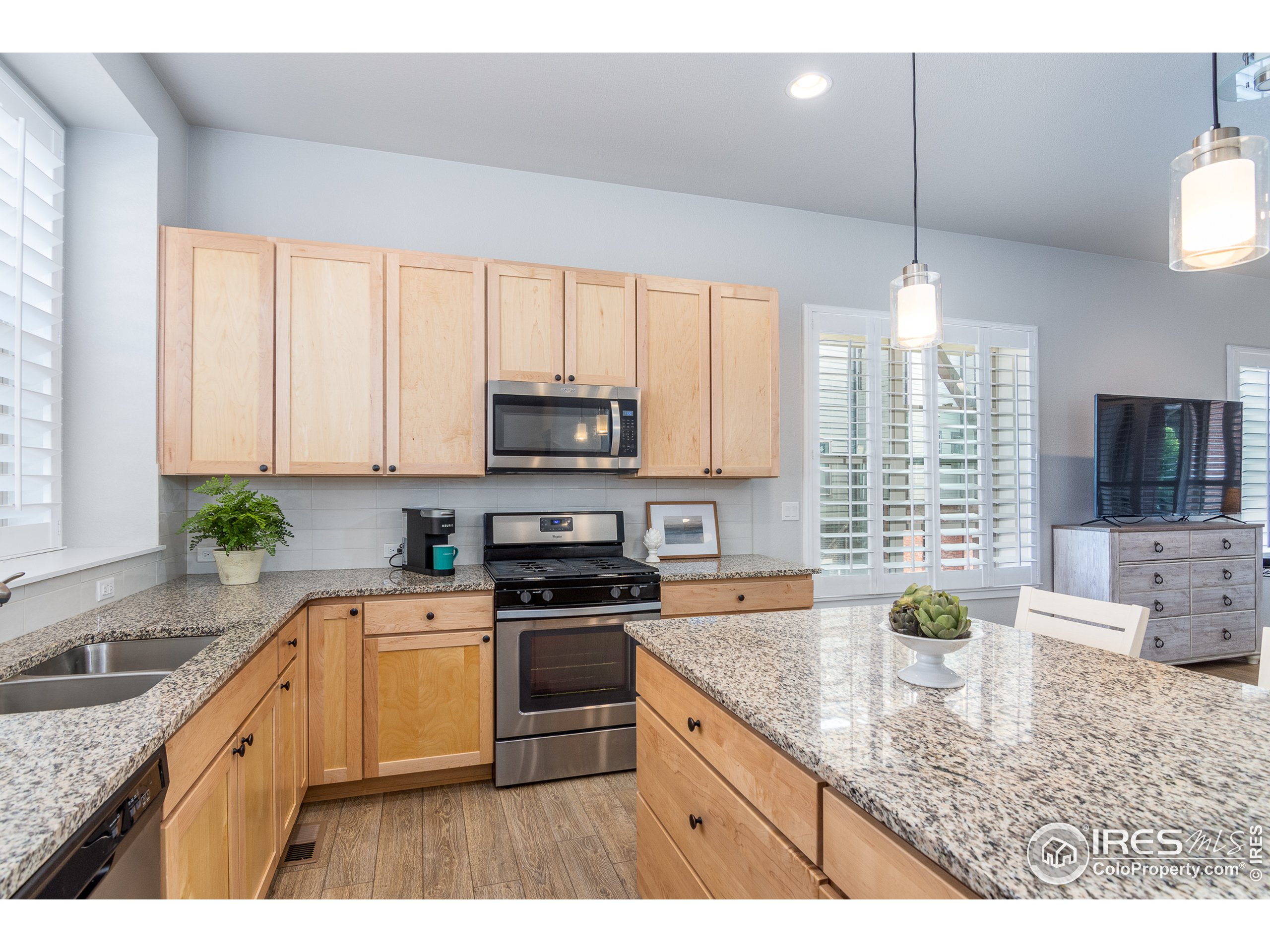 a kitchen with stainless steel appliances granite countertop a sink a stove a oven a dining table and chairs