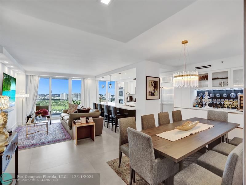 a living room with lots of furniture kitchen view and a chandelier