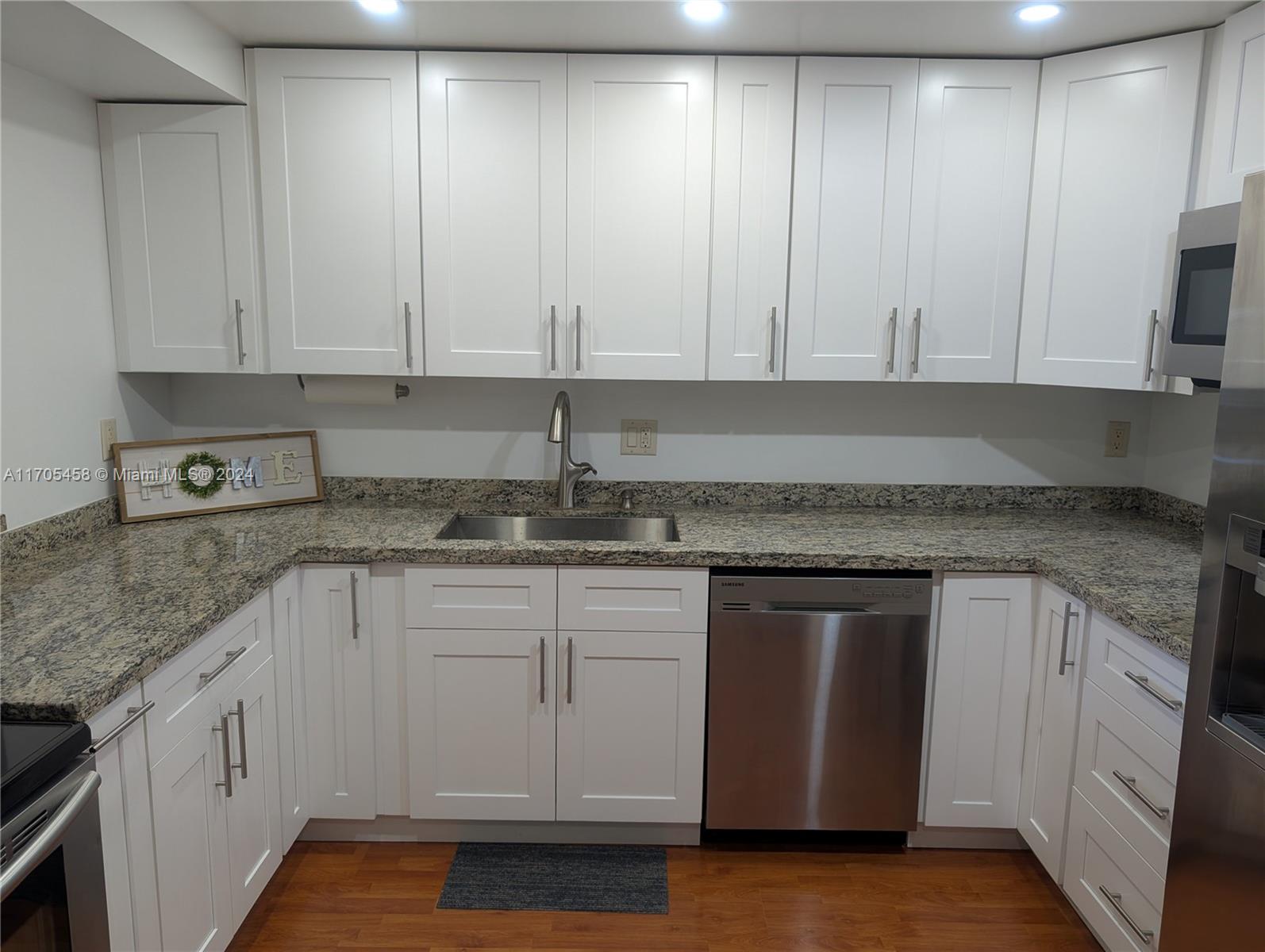 a kitchen with granite countertop white cabinets and stainless steel appliances