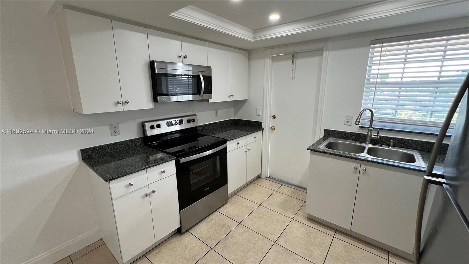 a kitchen with granite countertop a stove sink and microwave