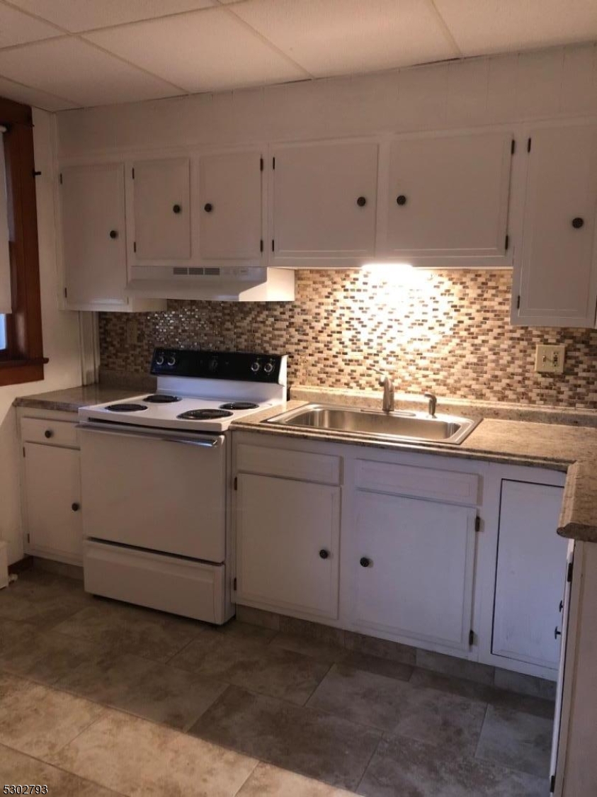 a kitchen with granite countertop white cabinets and white stainless steel appliances