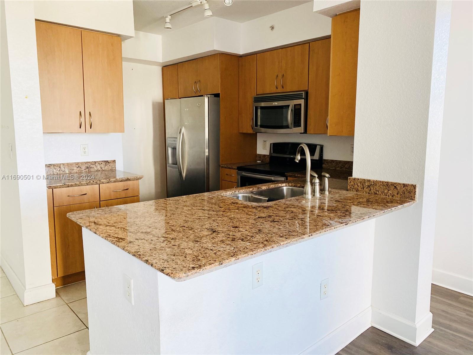 a kitchen with kitchen island sink and refrigerator