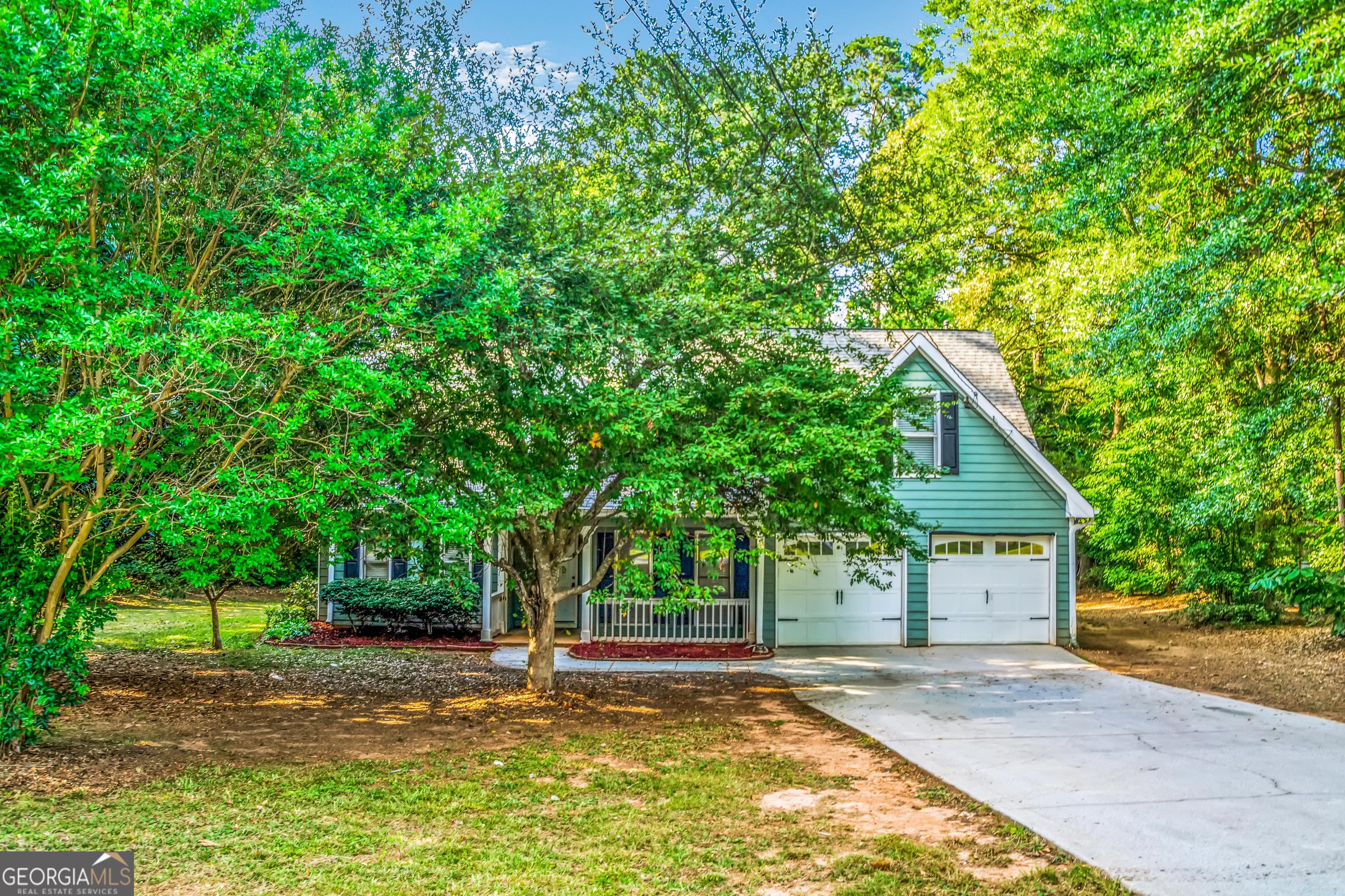 a view of a house with a yard and large tree