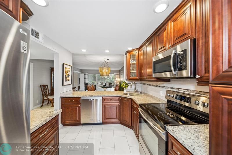 a kitchen with stainless steel appliances granite countertop a stove a sink dishwasher and a refrigerator