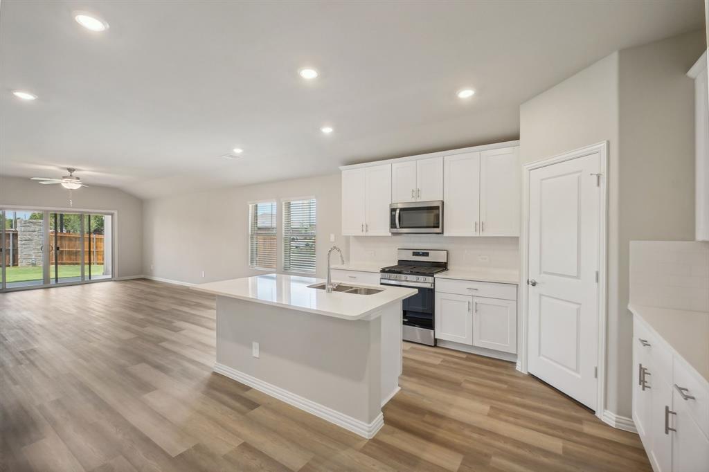 a large kitchen with stainless steel appliances granite countertop a stove and a refrigerator