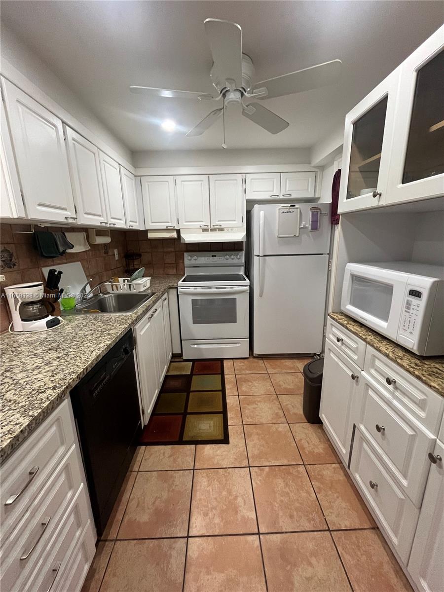 a kitchen with granite countertop a refrigerator stove and sink