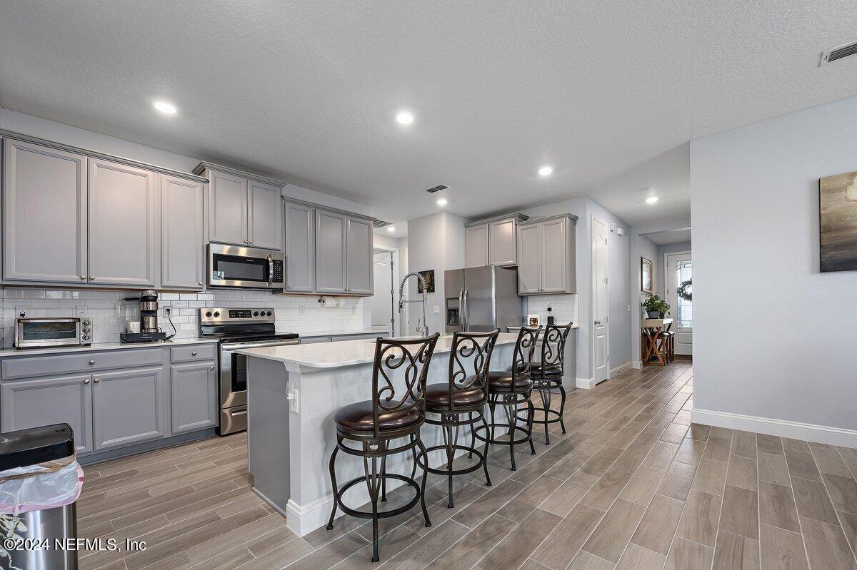 a kitchen with a dining table chairs wooden cabinets and stainless steel appliances