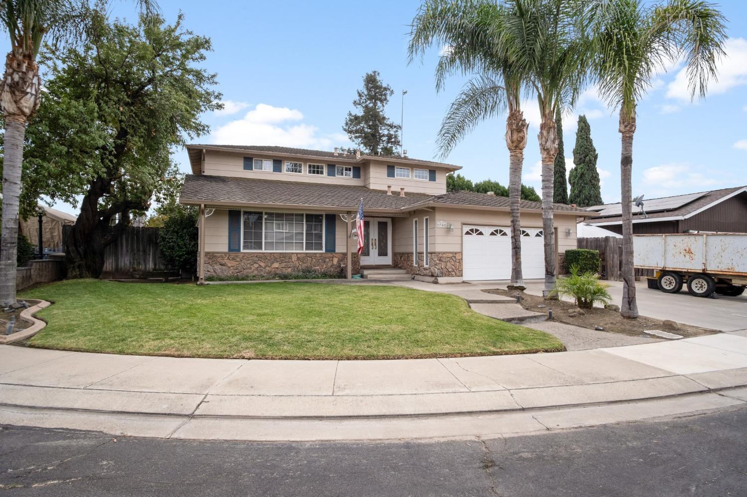 a front view of a house with a garden and tree