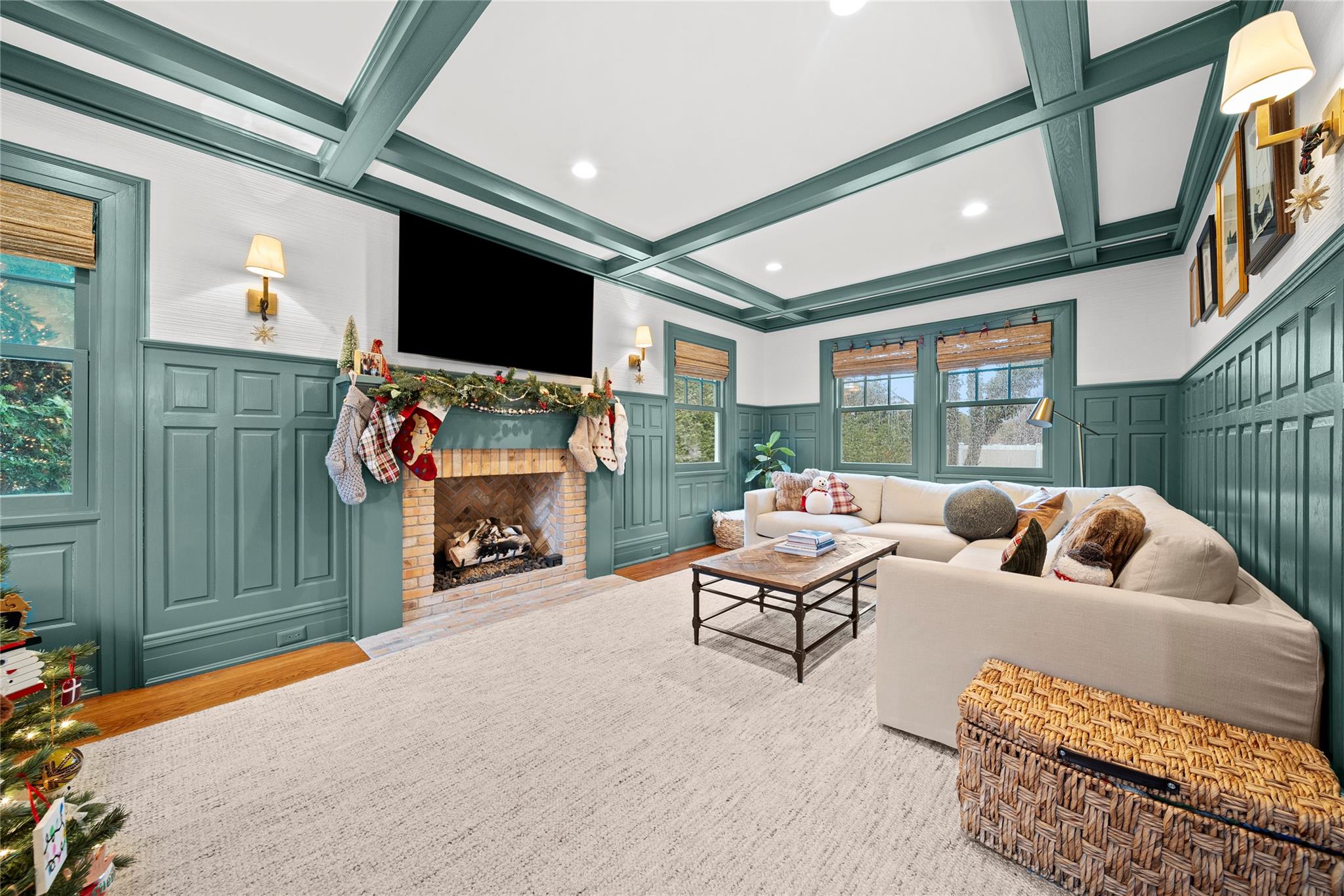 Living room featuring a brick fireplace, beam ceiling, light wood-type flooring, and coffered ceiling