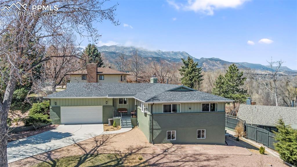 a front view of a house with a yard and mountain view in back