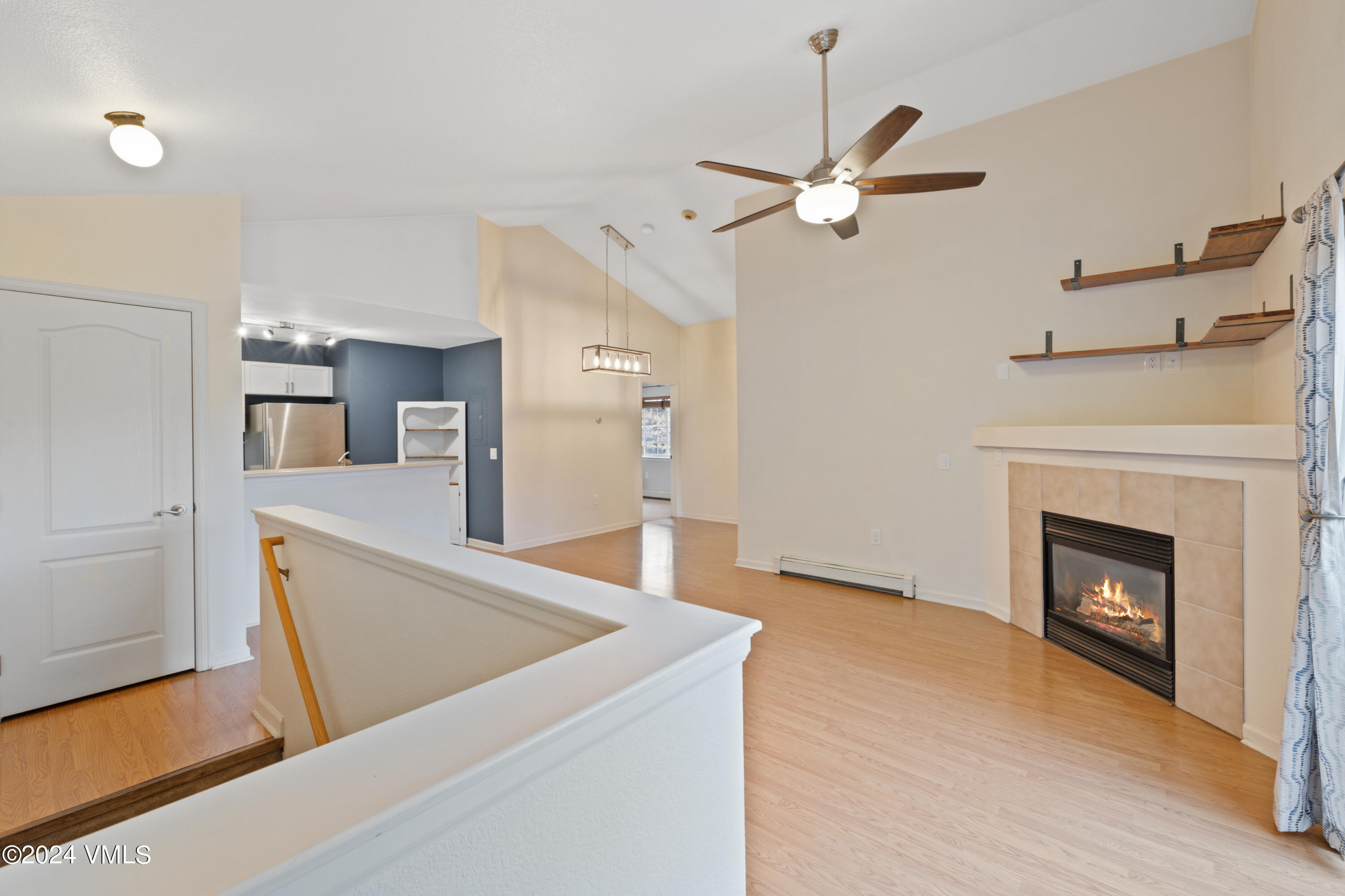 a living room with stainless steel appliances wooden floor and a fireplace