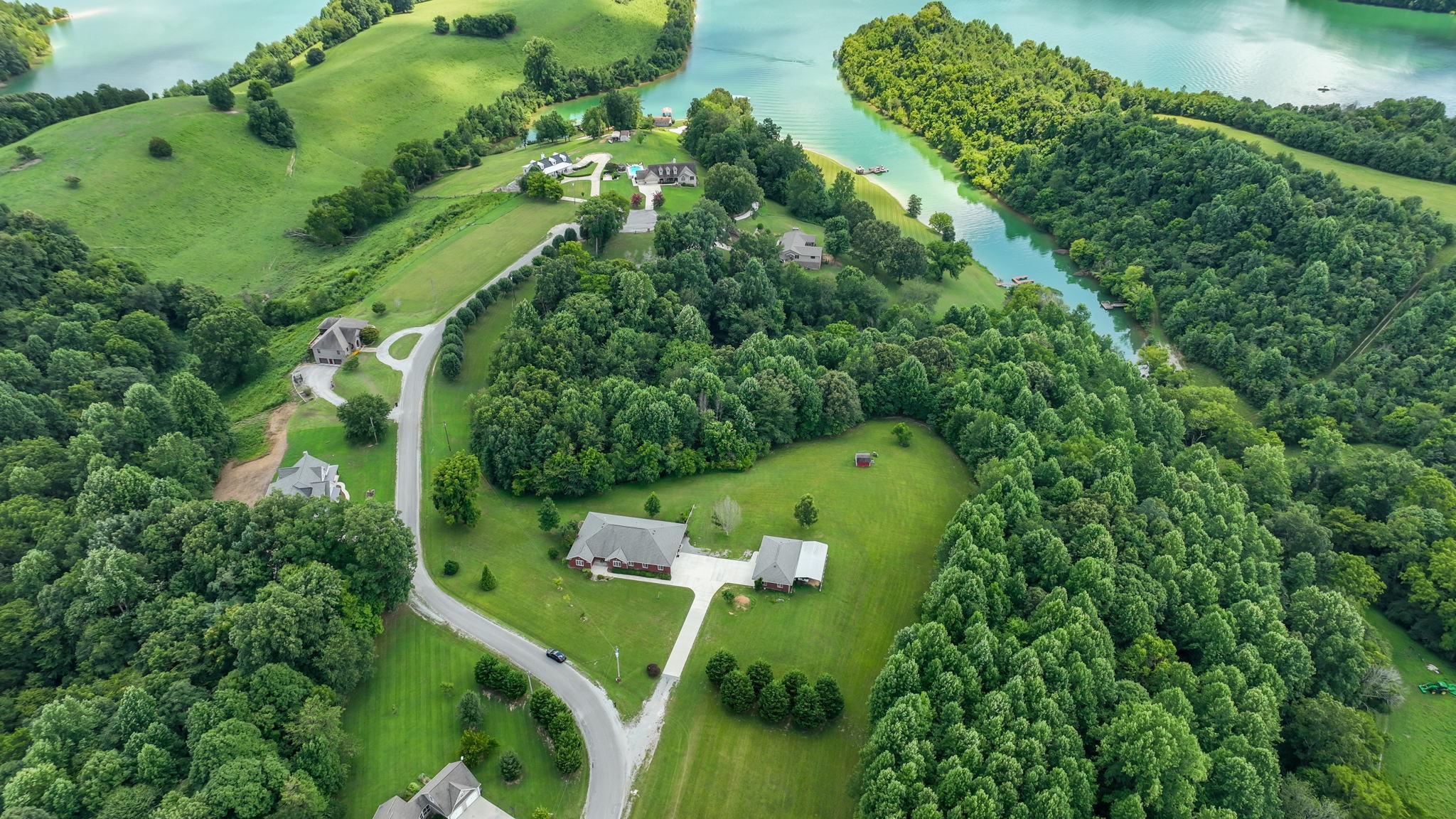 an aerial view of a residential houses with outdoor space and trees all around