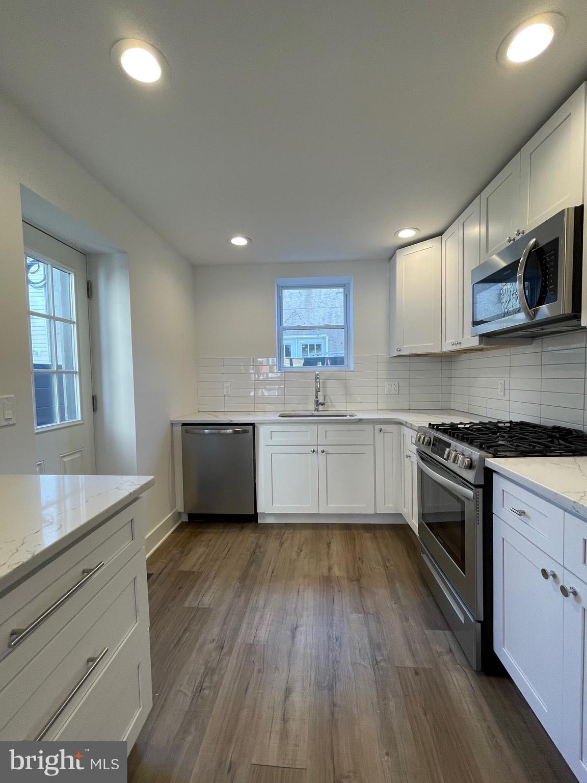 a kitchen with stainless steel appliances a sink cabinets and wooden floor