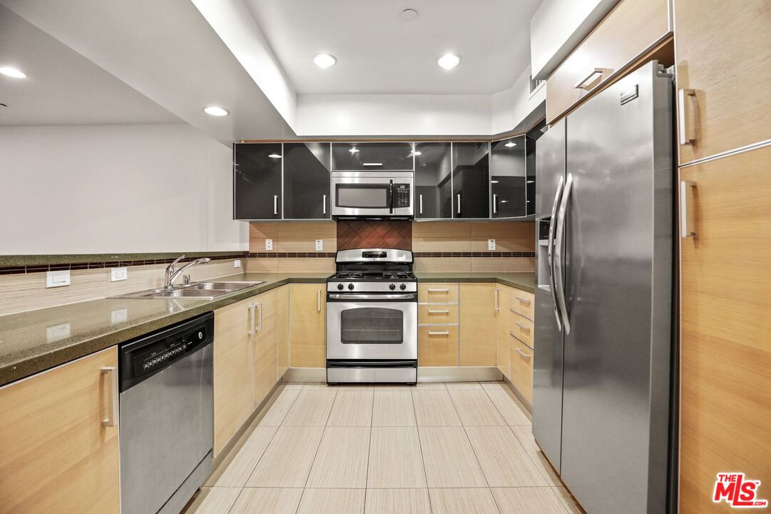 a kitchen with stainless steel appliances granite countertop a refrigerator and a sink