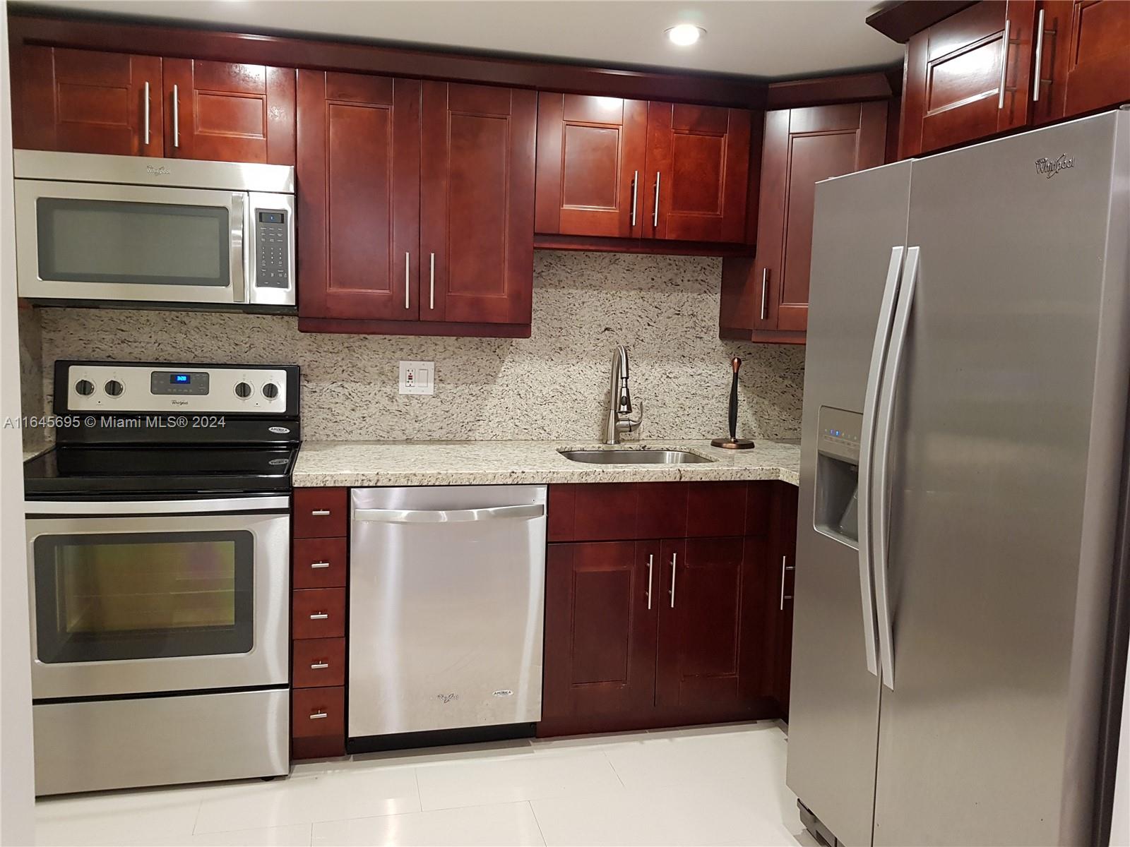 a kitchen with stainless steel appliances granite countertop a refrigerator stove and microwave