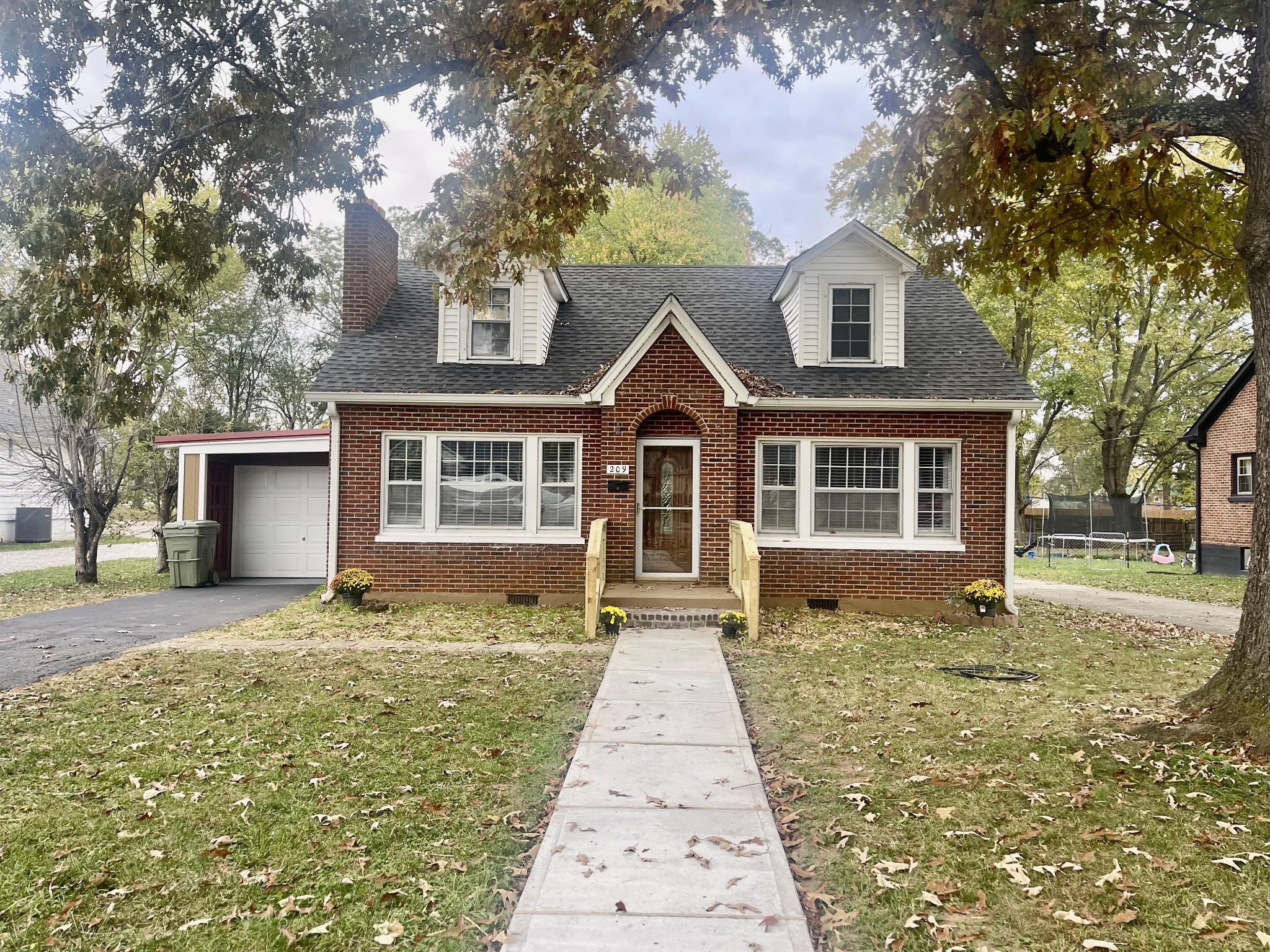 a front view of a house with a garden and trees